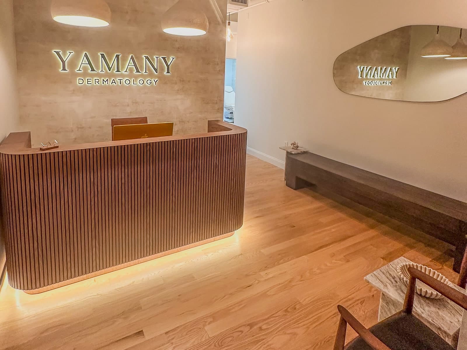 Yamany Dermatology reception area with curved wooden desk and warm, modern design