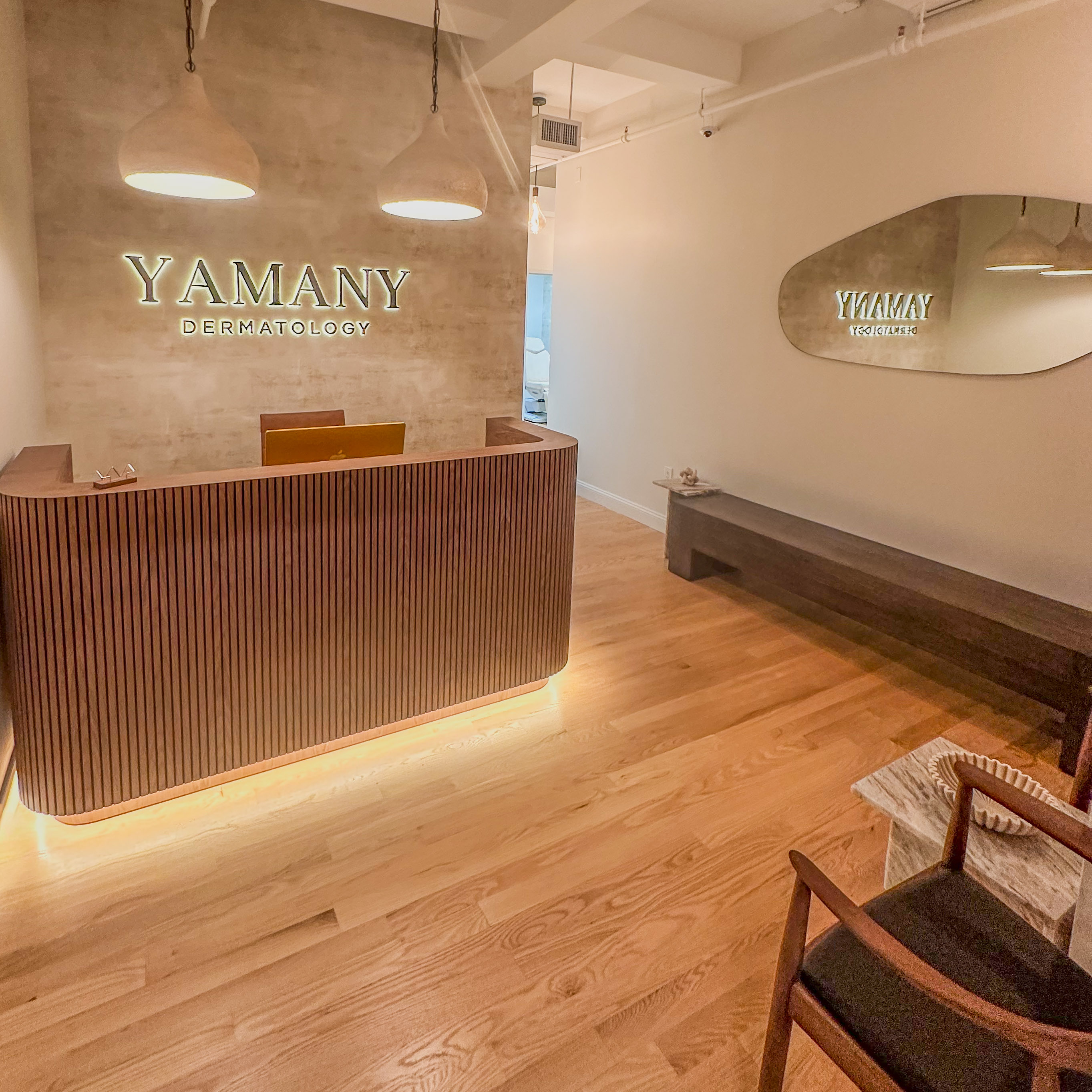 Yamany Dermatology reception area with curved wooden desk and warm, modern design